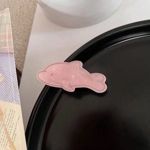 Nahaufnahme der rosa glitzernden Acryl-Delfin-Haarspange mit schimmernder Textur