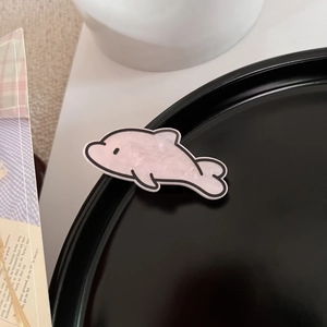 Nahaufnahme der rosa Delphin Haarklammer aus Acryl mit Marmormuster auf Tablett