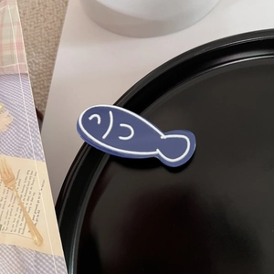 Makro-Detail einer blauen Fisch-Haarklammer aus Acryl auf einem dekorativen Tablett