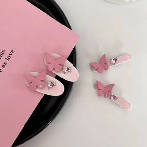 Détail de pinces à cheveux papillon rose avec strass et cœurs pour un style élégant