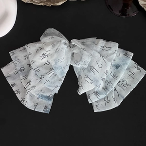 Detail of white chiffon hair clip with artistic black ink calligraphy print pattern