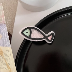 Detail einer niedlichen Haarspange in Fischform mit Perlmutteffekt und grünen Akzenten