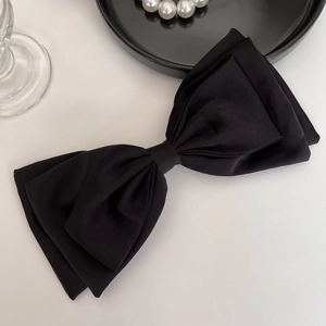 Barrette nœud papillon géante en satin noir sur fond blanc avec collier de perles