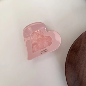Détail d'une pince à cheveux cœur rose avec texture marbrée et texte Barrette la France