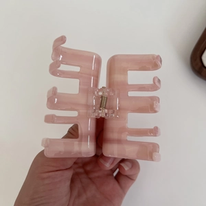 Pink translucent acetate hair claw clip with striped texture and golden metal spring