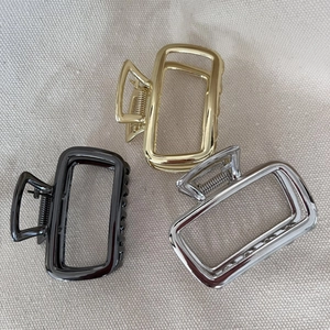 Three minimalist hollow rectangular metal hair claws in gold, silver, and black finishes
