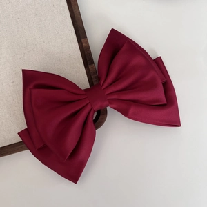 Detail of burgundy satin bow hair clip with multi-layered 3D vintage texture