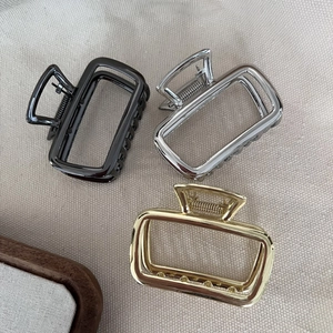 Three metallic square hair claw clips in gold, silver, and gunmetal finishes on fabric