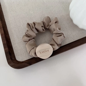 Elegant milk tea color satin scrunchie with Lucky pendant on minimalist fabric hair tie
