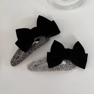 Pair of vintage velvet bow hair clips featuring sparkling rhinestones on plain background