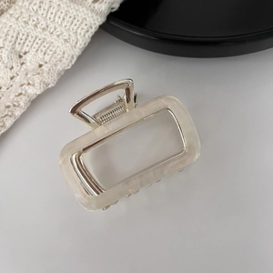 Detail of a creamy white acetate hair claw clip with a polished silver metal spring