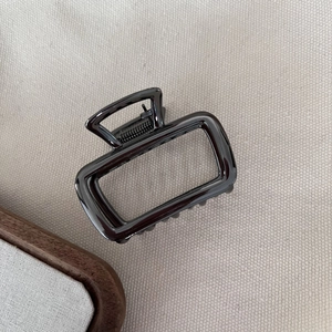Detailed view of square hollow metal hair claw clip in gunmetal finish on canvas