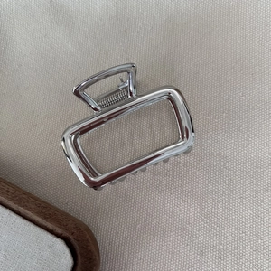 Macro shot of rectangular silver metal hair claw clip with polished mirror finish texture