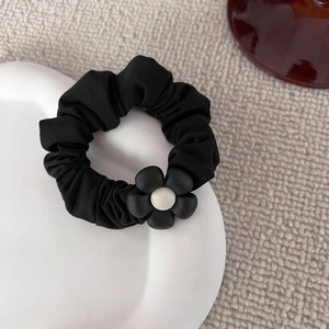 Elastico per capelli nero con fiore bianco e nero minimalista su un piatto di ceramica