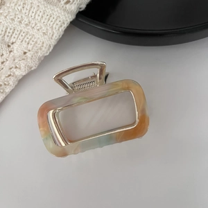 Detail view of square marble acetate hair claw clip with golden metal frame and spring