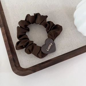 Detail of dark brown satin scrunchie with a heart-shaped Lucky engraved gold buckle