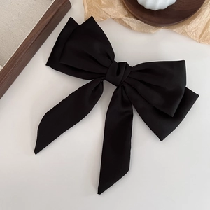 Macro shot of large black satin double-layered bow hair clip with elegant long ribbons