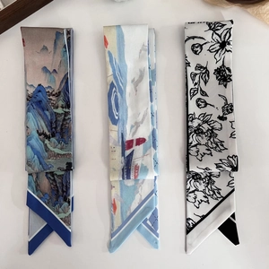 Three long skinny silk scarves featuring landscape, lighthouse, and floral art designs