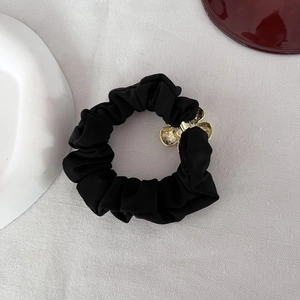 Dettaglio dell'elastico nero con fiore in metallo dorato su sfondo di tessuto bianco puro