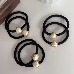 Vue détaillée des élastiques à cheveux noirs avec ornements en perles trèfle et cœur