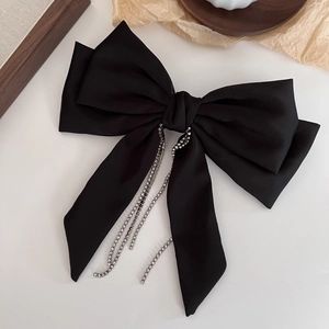 Elegant black satin bow hair clip with luxury long rhinestone fringe on wooden background