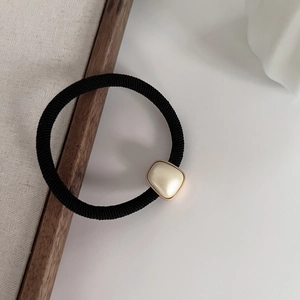 Détail de l'élastique noir avec perle crème et bordure dorée de style rétro