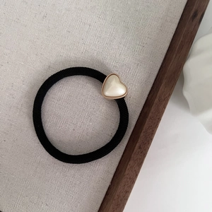 Détail de l'élastique noir à haute élasticité avec perle en cœur et cadre en métal rose doré