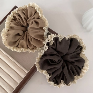 Close-up of brown and beige chiffon scrunchies with intricate cream crochet lace edges