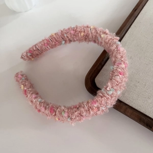 Detail of pink knitted headband featuring colorful yarn dots and soft textured fabric