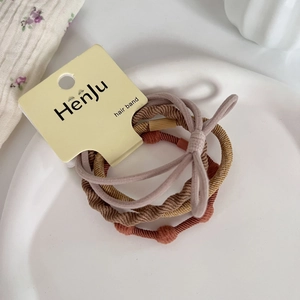 Close-up of earth-toned high elasticity hair ties set on a white ceramic plate
