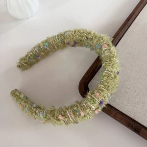 Detail of green knitted headband featuring colorful fuzzy textures and soft wool fabric