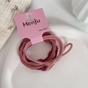 Detail of high-elasticity hair bands in pink and wine red colors on a ceramic tray