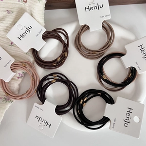 Set of 6 durable elastic hair bands in earthy tones with bronze beads on a tray