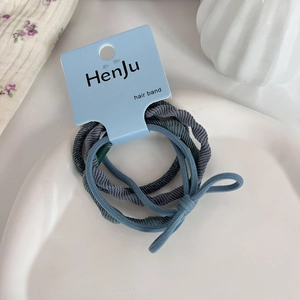 Detail of high-elasticity hair bands in muted tones with a bow on white ceramic tray