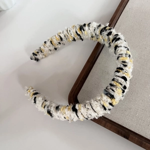Close-up of tricolor knitted headband with textured black white and yellow boucle fabric