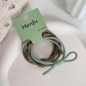 Detail of high-elasticity hair bands in grey, olive, and blue on a ceramic plate
