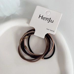 Detail of durable elastic hair bands with golden metallic beads on a white tray