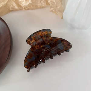 Detail of tortoiseshell acetate claw clip with Barrette La France text on wood tray