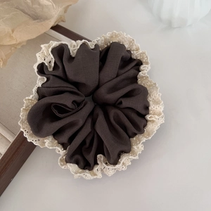 Detail of coffee brown fabric scrunchie with beige vintage crochet lace edging