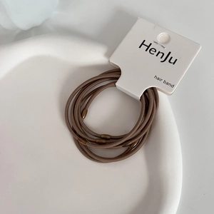 Detailed macro view of bronze elastic hair bands with golden beads on a white tray