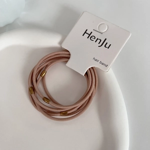 Close-up of pink elastic hair bands with gold metal cylinders on white ceramic tray