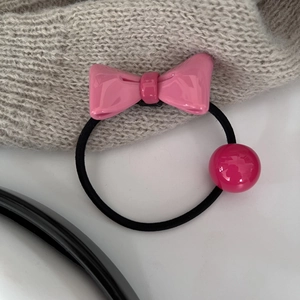 Rosa Schleife und glänzende Perle auf grauem Strickhintergrund Haarband