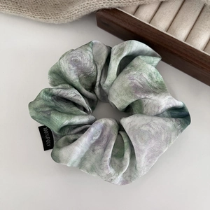 Detailed close-up of marble texture satin scrunchie with brand wash label details