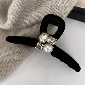 Elegant black velvet claw clip with rhinestones and white pearl on a warm knit surface