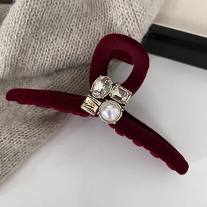 Detailed close-up of dark red velvet hair claw clip with rhinestones and white pearl