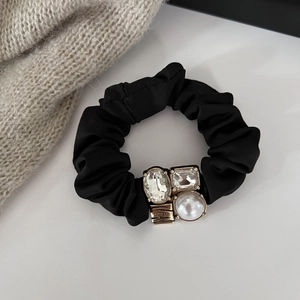 Detail of black velvet scrunchie with crystal square and pearl on gold metal setting