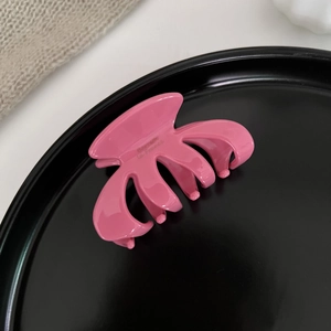 Close-up of pink glossy pumpkin hair claw clip on black plate showing detailed teeth