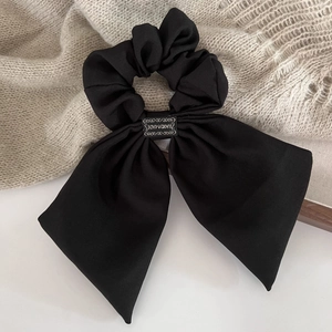 Détail d'un chouchou noir fait main avec nœud en sergé sur fond de tricot doux