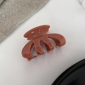Detail view of a glossy caramel brown pumpkin claw clip with professional finish