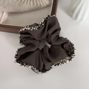 Detail view of coffee brown scrunchie with textured fabric and elegant fringe trim